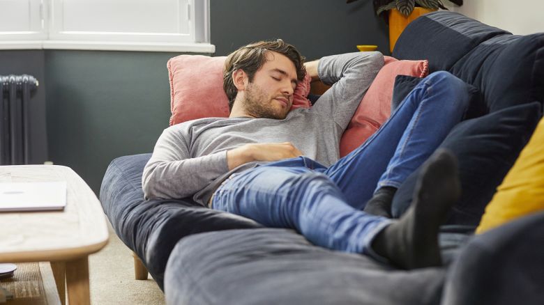 Young white man with beard asleep on sofa.