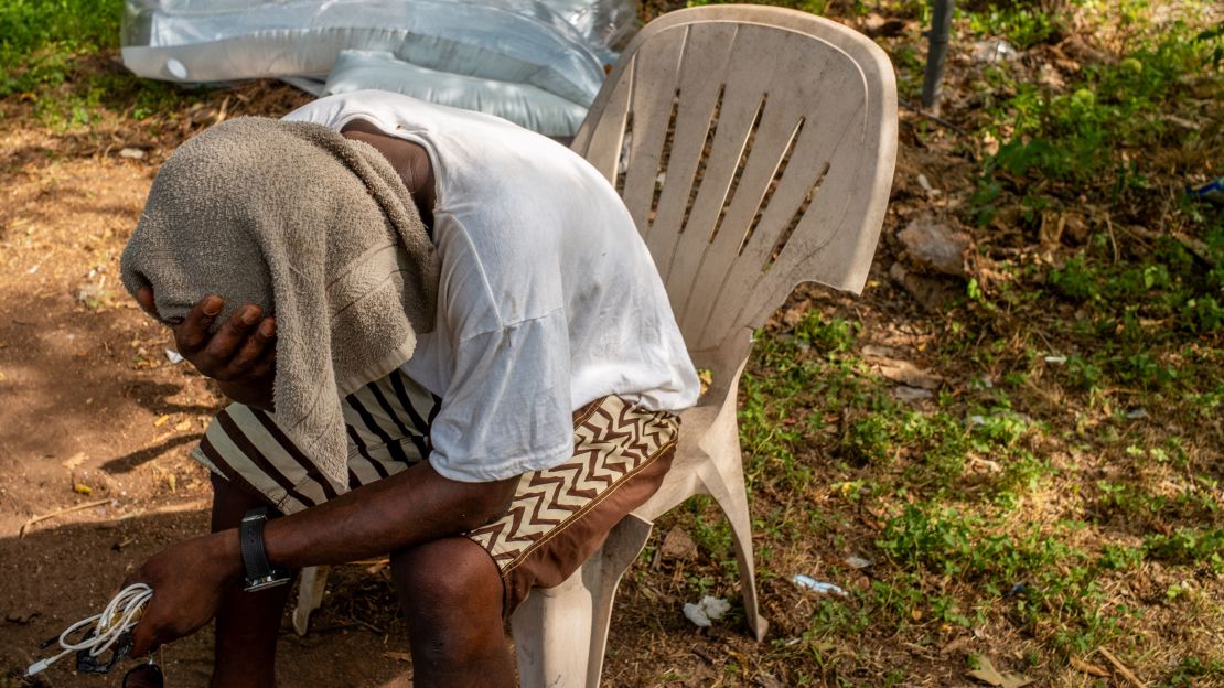 A man sits with a towel over his head in the shade on June 19, 2023, in Austin, Texas.