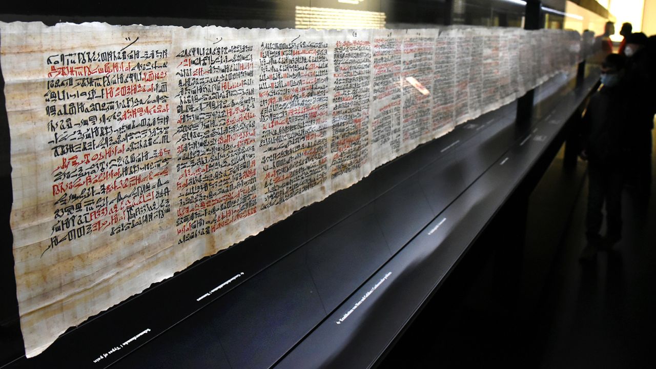 21 February 2022, Saxony, Leipzig: Visitors look at a replica of the 3500-year-old Papyrus Ebers, the largest scroll on the medical science of ancient Egypt, in the showroom of the Albertina University Library. The 18.63-meter-long papyrus scroll, the original of which is kept in the library, contains almost 900 recipes and texts of general and internal medicine for 80 diseases and the corresponding remedies written in red and black ink on the front and back. The Papyrus Ebers is one of the most important sources of our knowledge about the medicine of antiquity. Photo: Waltraud Grubitzsch/dpa-Zentralbild/ZB (Photo by Waltraud Grubitzsch/picture alliance via Getty Images)