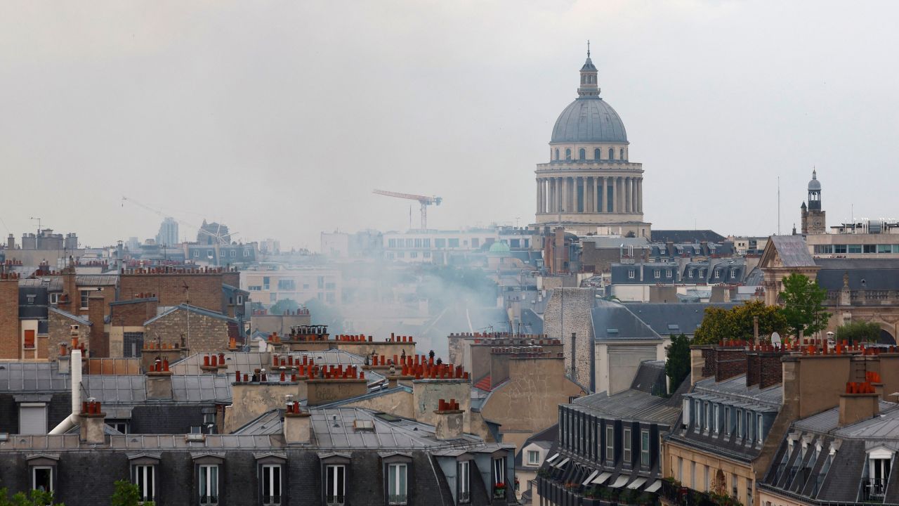 Smoke rises above rooftops with the Pantheon in the background.