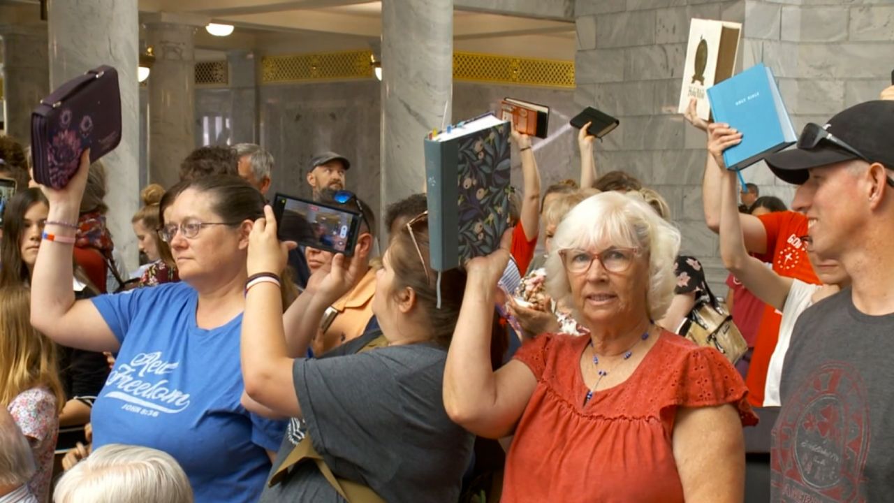 People raise their bibles in at the Utah State Capitol on June 7,  protesting that the book was removed from  Davis County schools.