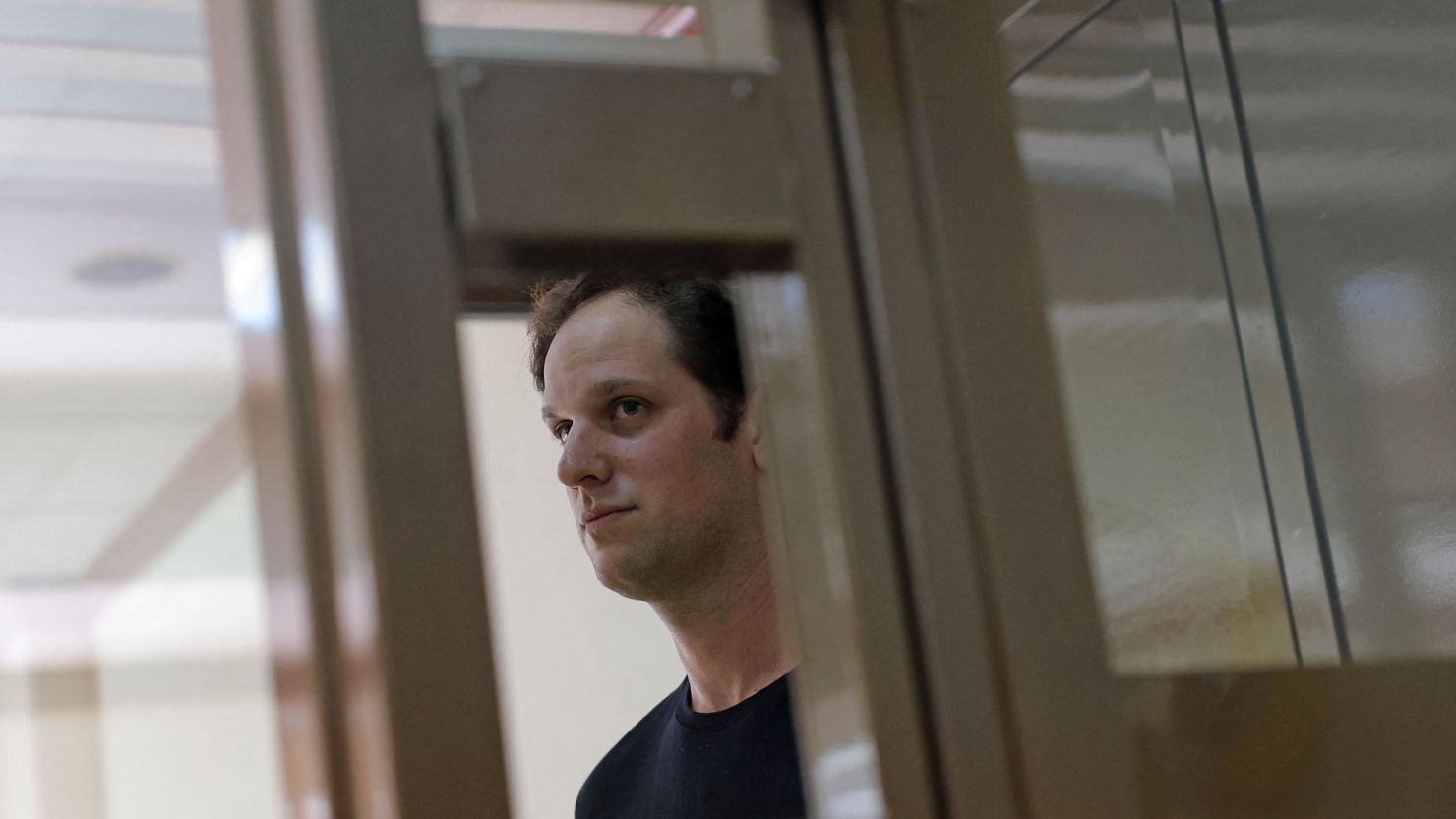 Wall Street Journal reporter Evan Gershkovich, who was arrested in March while on a reporting trip and accused of espionage, stands behind a glass wall of an enclosure for defendants before a court hearing to consider an appeal against his detention, in Moscow, Russia June 22, 2023. REUTERS/Evgenia Novozhenina
