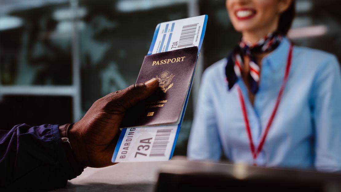 African American man holding boarding pass and passport at airline check-in desk at international airport