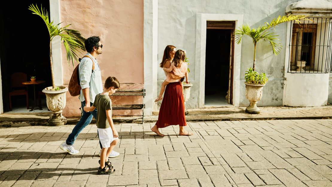 Wide shot of family walking down street while exploring town during vacation in Yucatan, Mexico