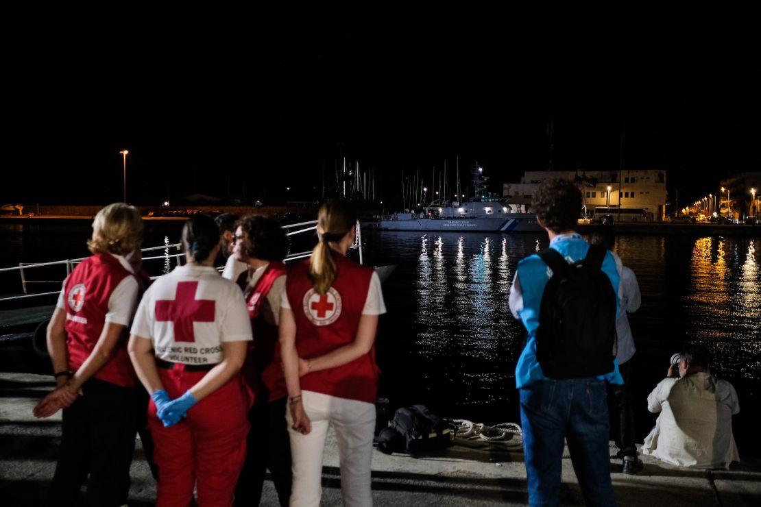 Members of the Red Cross and UNHCR outside a migrant hangar as a coast guard ship carrying 79 bodies arrives into the Greek port of Kalamata.