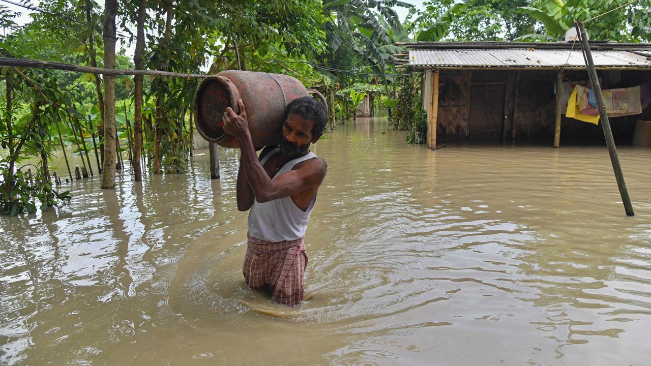 A man carries belongings from his partially submerged house in the flood affected Dhamdhama village of Nalbari district, in India's Assam state on June 22, 2023.