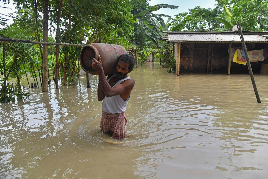 A man carries belongings from his partially submerged house in the flood affected Dhamdhama village of Nalbari district, in India's Assam state on June 22, 2023.