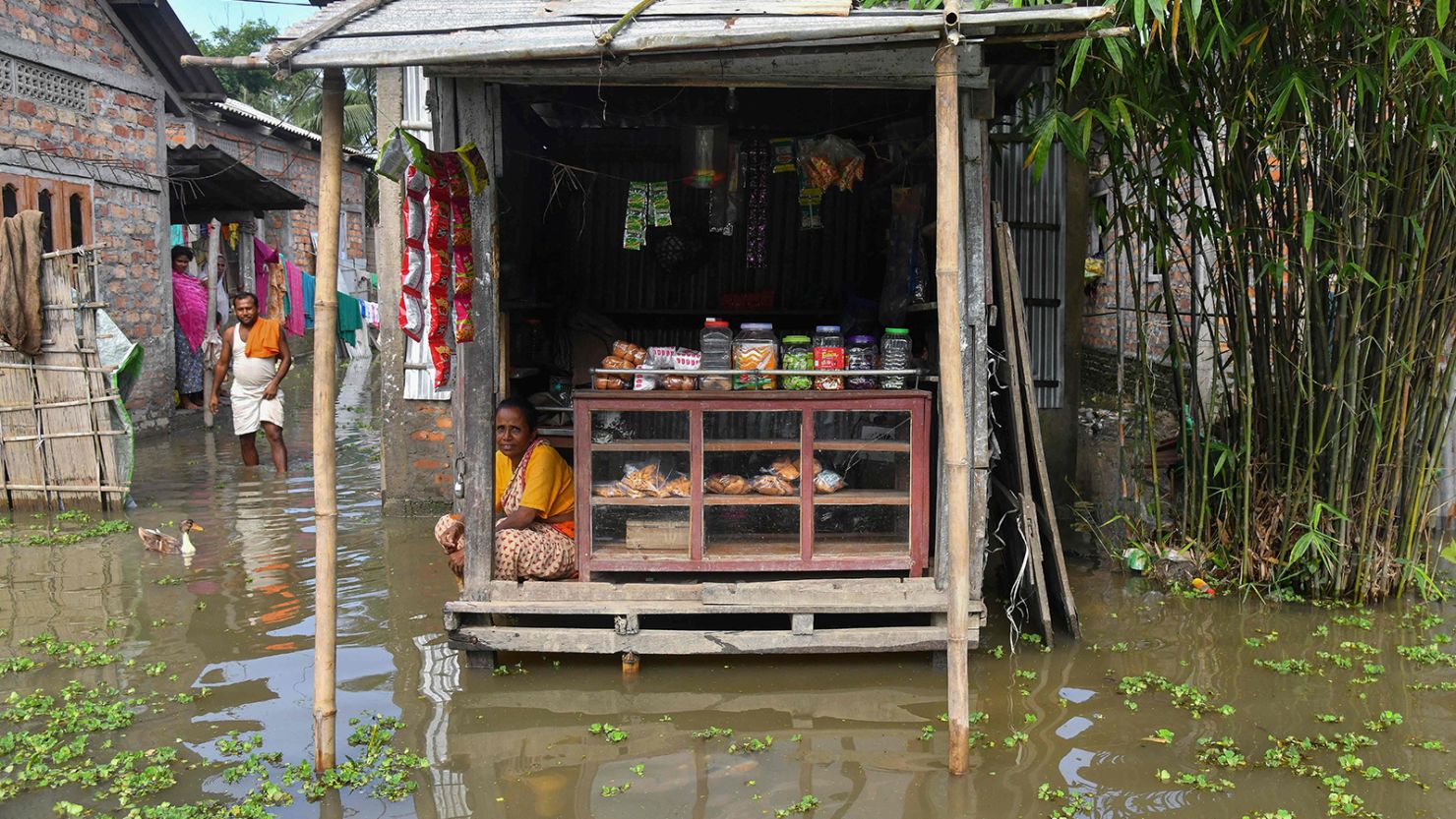A woman sits at her partially submerged shop in the flood affected area of Rangia, in India's Assam state on June 22, 2023. 