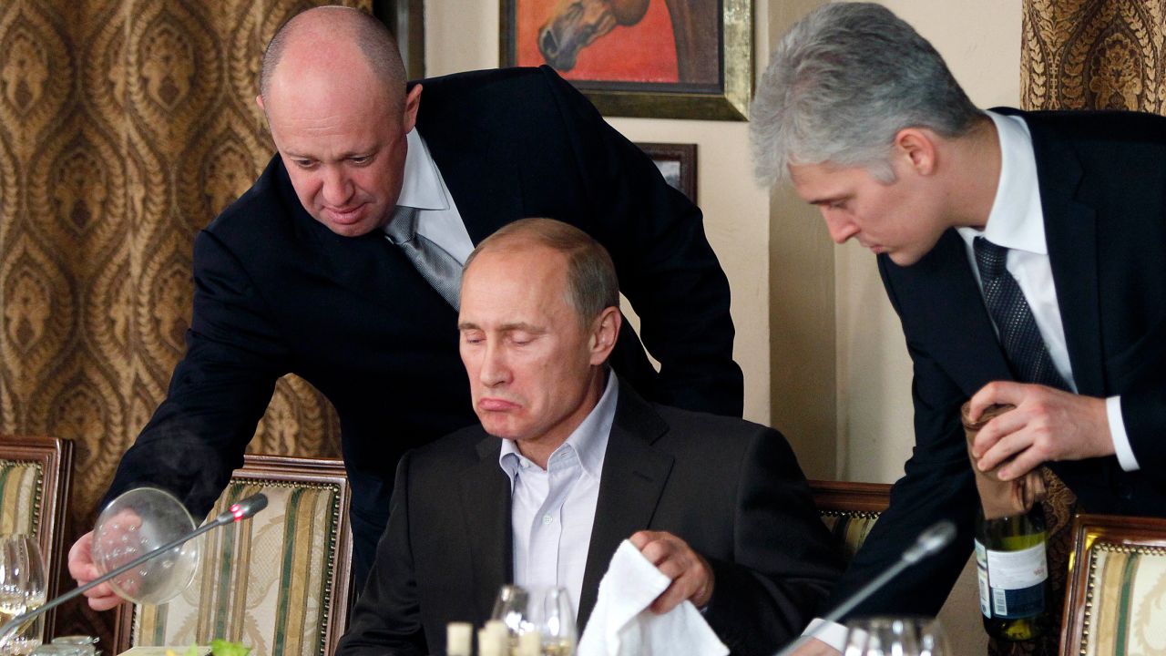  Пригожин, вляво, сервира храна на руския премиер Владимир Путин, в средата, по време на вечеря в ресторанта на Пригожин извън Москва, Русия през ноември 2011 г. 