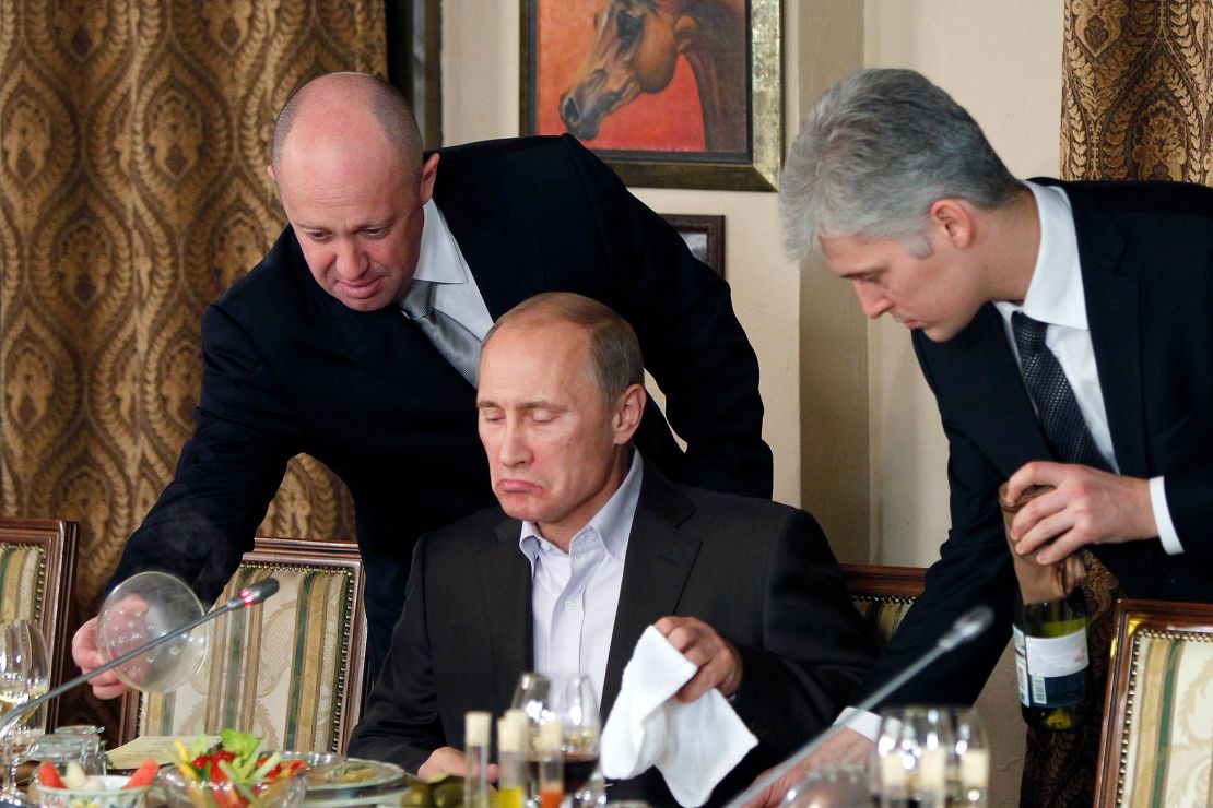 Prigozhin, left, serves food to Russian Prime Minister Vladimir Putin, center, during dinner at Prigozhin's restaurant outside Moscow, Russia in November 2011. 