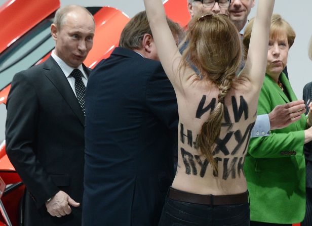 A topless demonstrator with a message on her back walks toward Putin and German Chancellor Angela Merkel in Hanover, Germany, in April 2013.