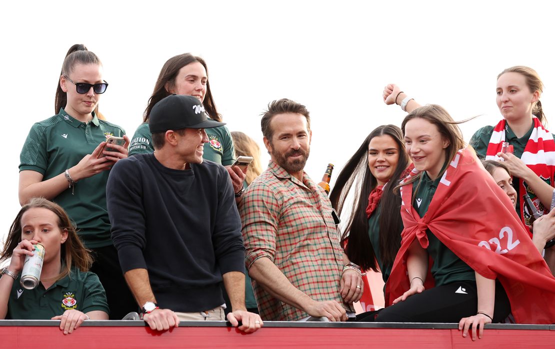 Rob McElhenney, Co-Owner of Wrexham, and Ryan Reynolds, Co-Owner of Wrexham, look on as they celebrate with players of Wrexham Women during a Wrexham FC Bus Parade following their Title Winning Season in the Genero Adran North on May 2, 2023 in Wrexham, Wales.