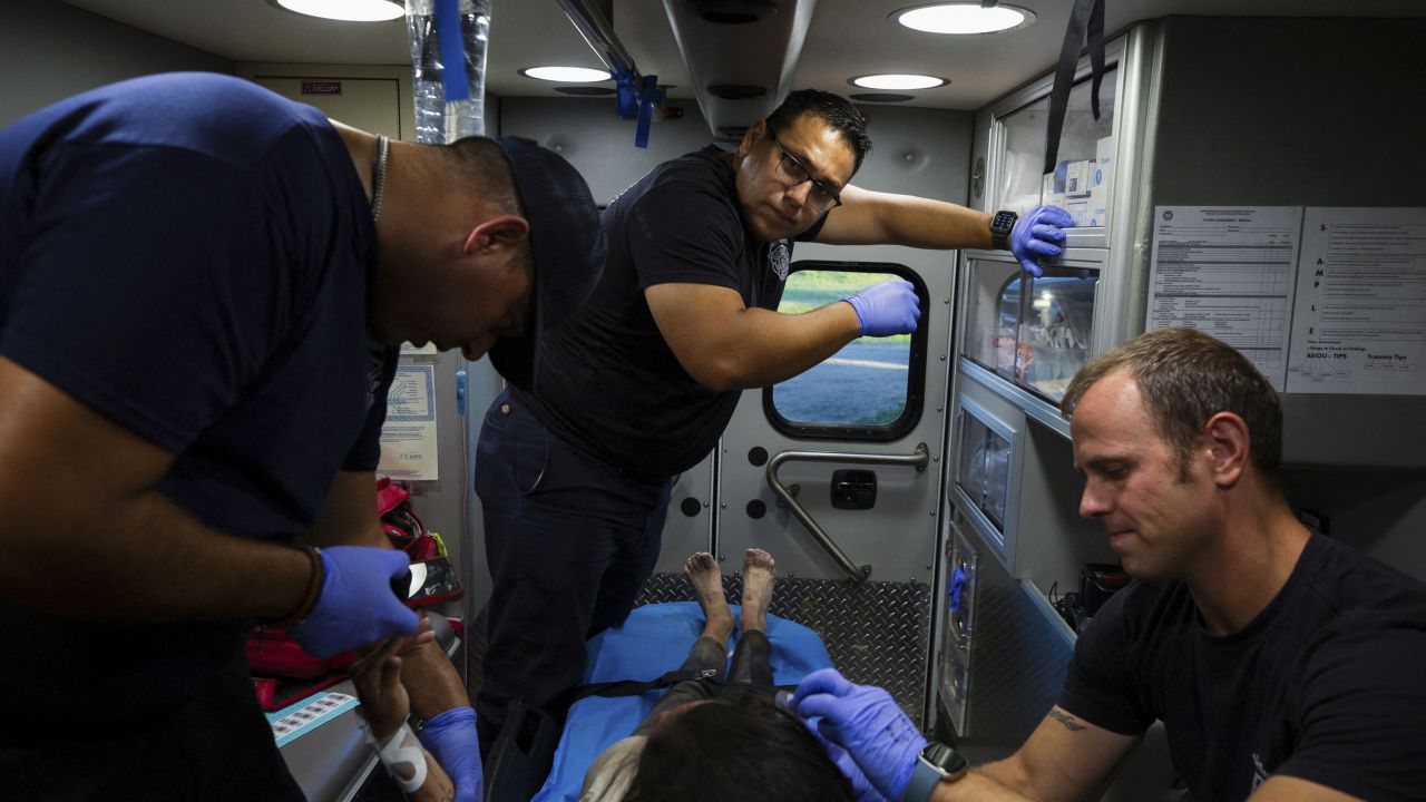 Firefighter EMT Rodrigo Pineda, firefighter EMT Jose Balino and firefighter EMT William Dorsey treat a migrant woman suffering from heat exhaustion in the border community of Eagle Pass, Texas, on Monday.