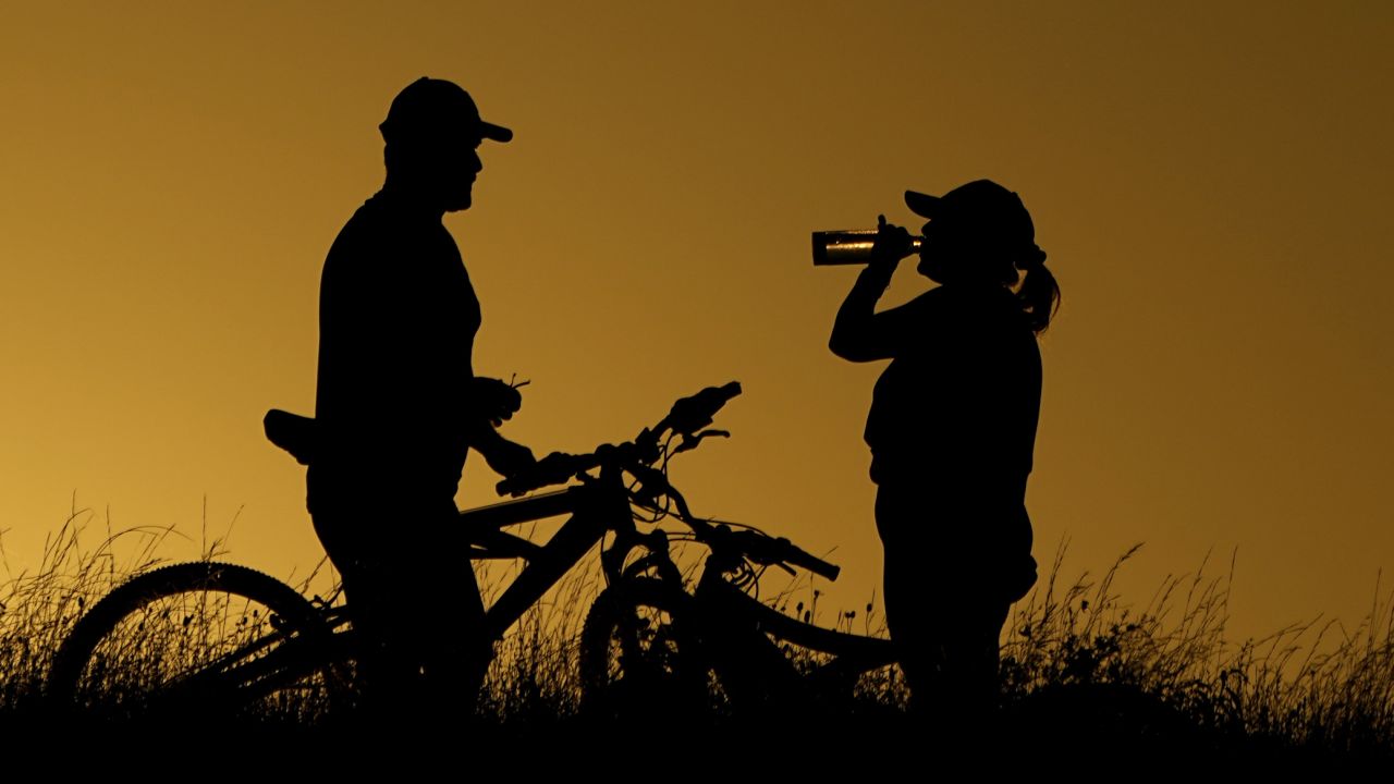 Cyclists take a water break during an evening ride Monday in San Antonio.