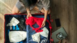 Top view woman packing suitcase for summer trip.