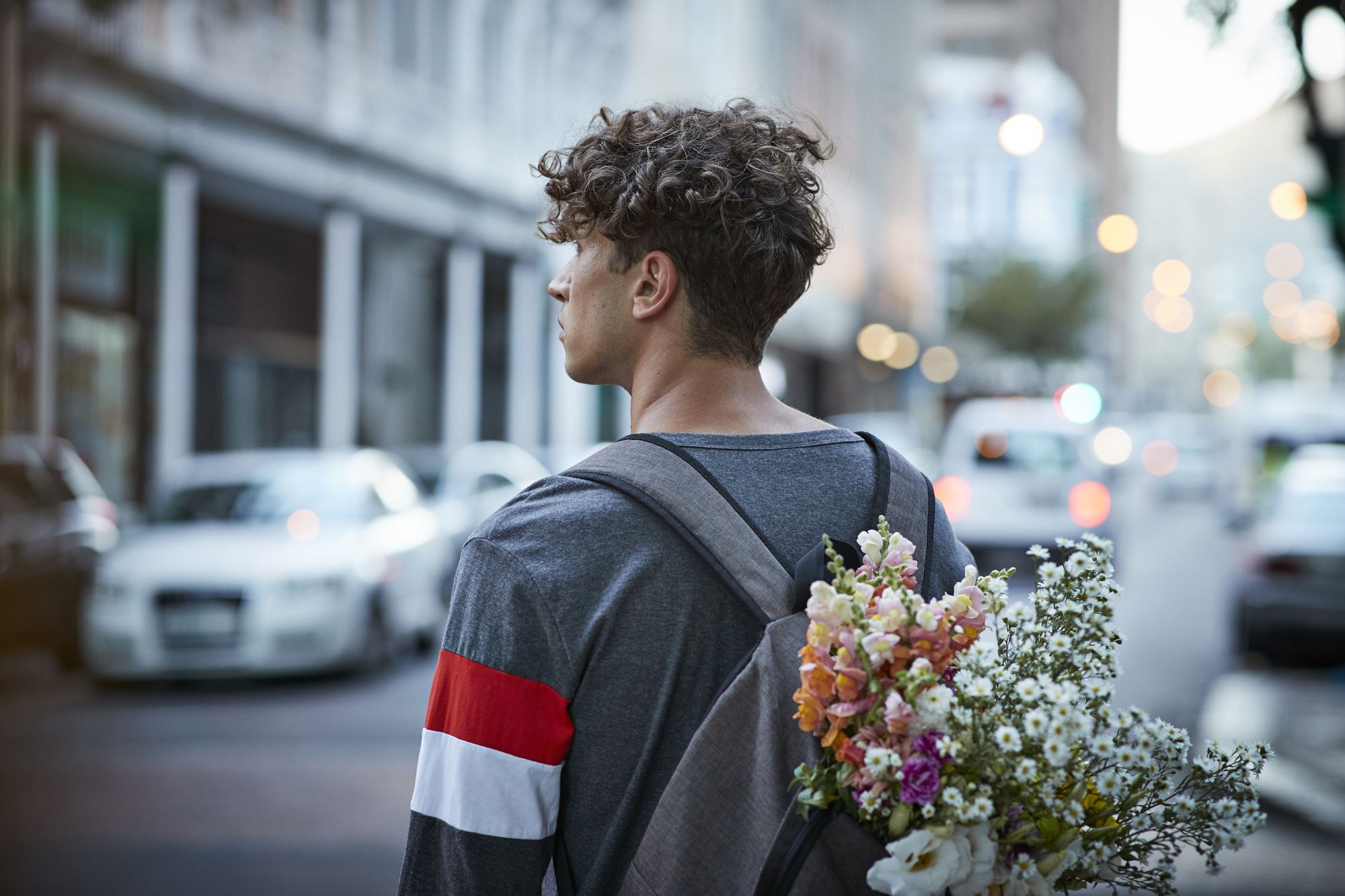 Young man on the street with flower in rug sack