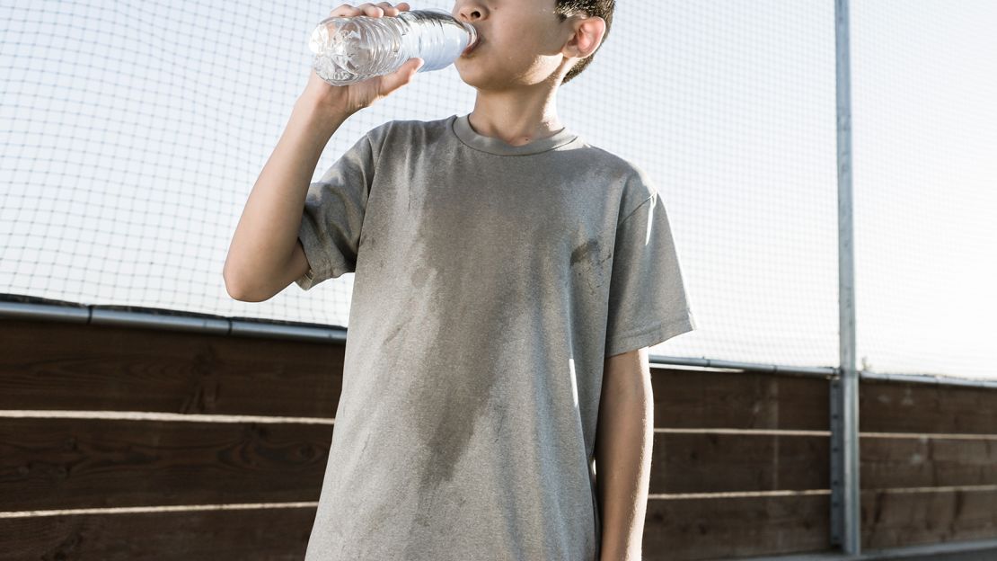 A young boy drinks water after a hard day of practice.