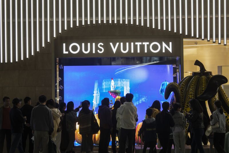 FILE--A woman rides an electric bike past a fashion boutique of Louis  Vuitton (LV) in Shanghai, China, 12 May 2015. Shanghai has emerged as the  mo Stock Photo - Alamy