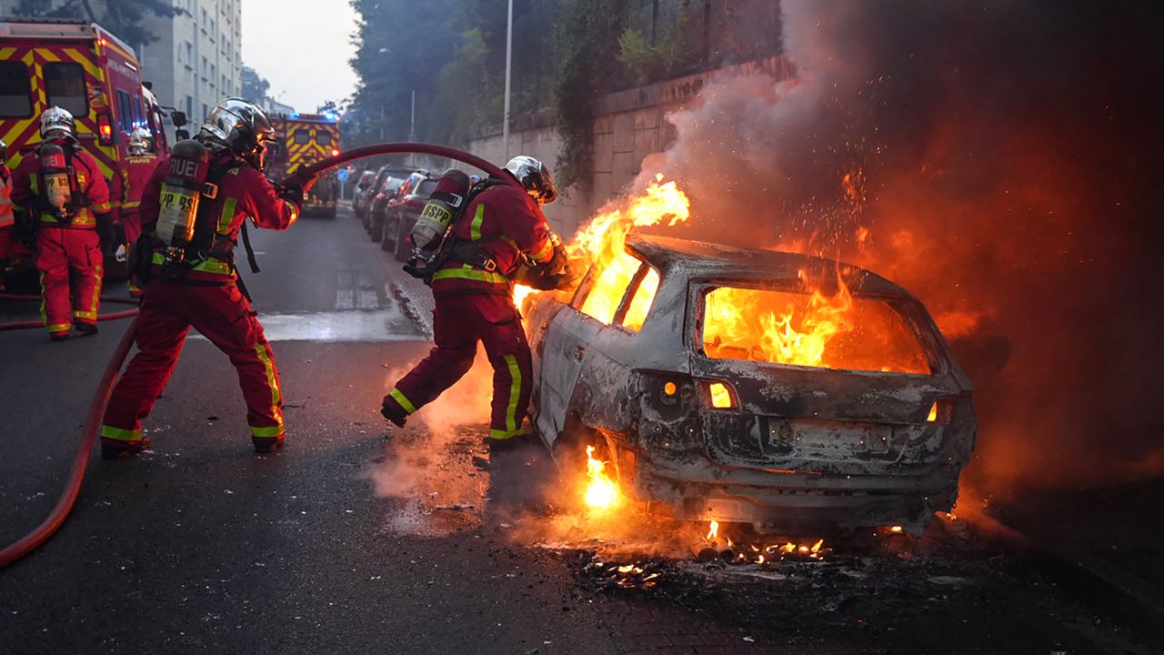 Firefighters work to put out a burning car at a protest in Nanterre, west of Paris, on June 27.