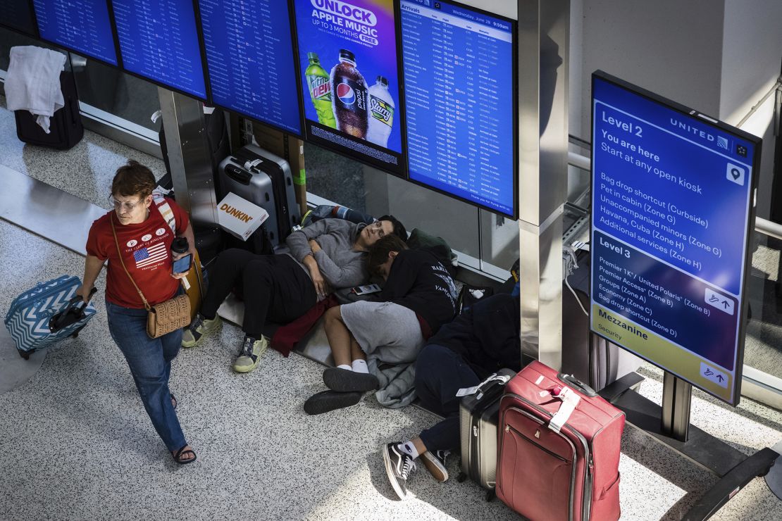 Delayed travelers sleep under the flight display screens at United Airlines' terminal in Newark International Airport on Wednesday.