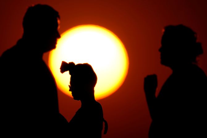 People are silhouetted against the setting sun in Kansas City on June 23.