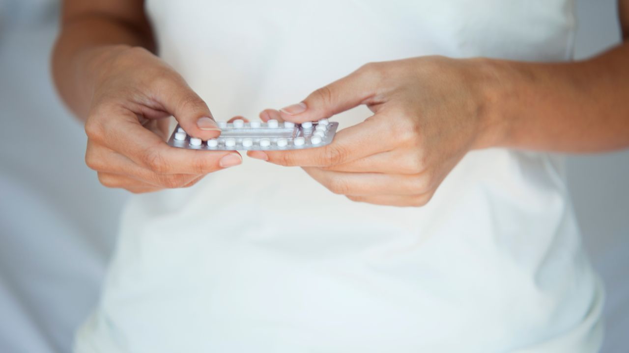 Woman holding birth control pills, mid section - stock photo