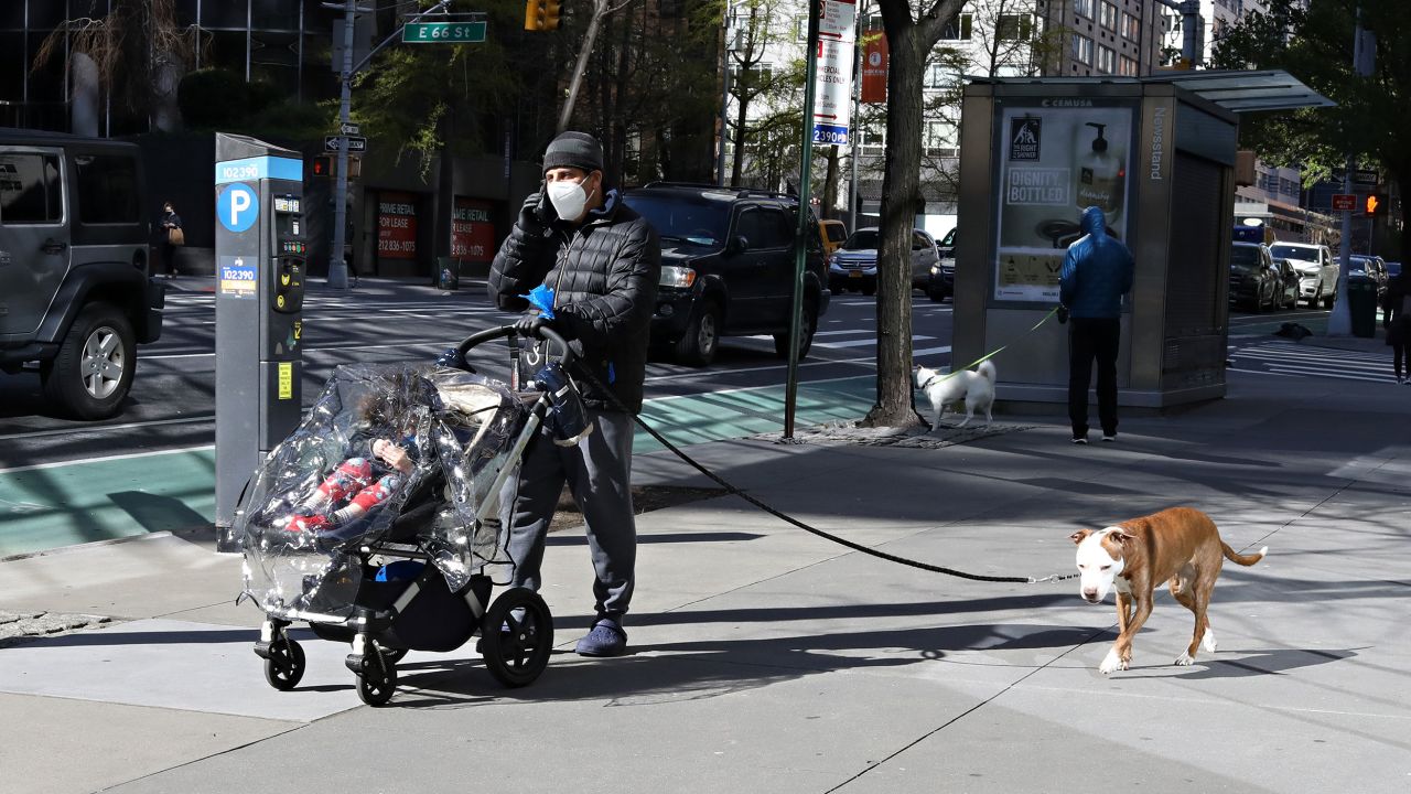 NEW YORK, NEW YORK - APRIL 22:  A man wearing a protective mask speaks on a cell phone while pushing a child in a stroller and walking a dog during the coronavirus pandemic on April 20, 2020 in New York City. COVID-19 has spread to most countries around the world, claiming over 184,000 lives lost with over 2.6 million infections reported.  (Photo by Cindy Ord/Getty Images)