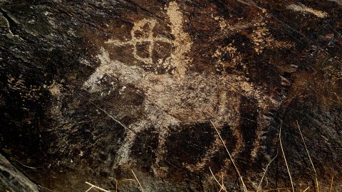 An ancient engraving of a hunter is seen in the hills outside the town of Khomein in central Iran on October 24, 2016. An Iranian archaeologist has spent years in an almost single-handed quest across the country's hills and desert plains to uncover ancient rock art that could be among the oldest in the world. Now he hopes that renewed ties with the West after years of international isolation could help decipher its mysteries. The Khomein hills are typical of rock art locations around the world -- a once-fertile riverside spot that supported sizeable settlements. As in other places around the world, the artists were fixated by a single image: in Iran, pictures of the ibex deer account for more than 90 percent of the ancient engravings (Photo by ATTA KENARE / AFP) (Photo by ATTA KENARE/AFP via Getty Images)