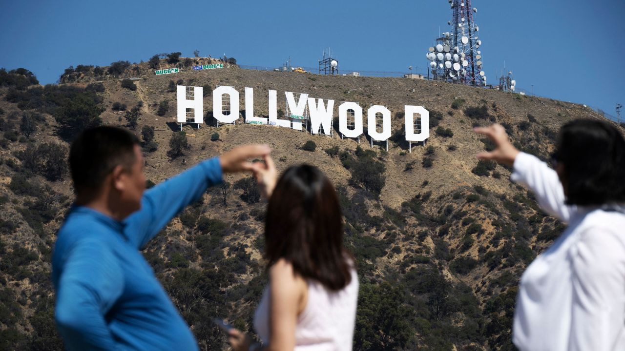 Visitors pose for snapshots in front of the Hollywood sign as it is repainted in preparation for its 100th anniversary in 2023, in Hollywood on September 28, 2022. - A team of 10 painters will work eight weeks and use almost 400 gallons of paint as the iconic Tinsletown landmark gets a makeover ahead of it's 100th anniversary in 2023. (Photo by Robyn Beck / AFP) (Photo by ROBYN BECK/AFP via Getty Images)