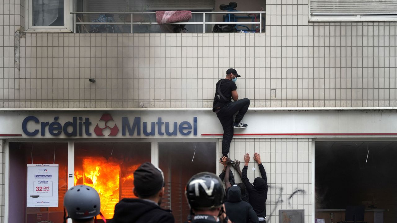Протестующий взбирается на здание во время столкновений, вспыхнувших в Нантере.
