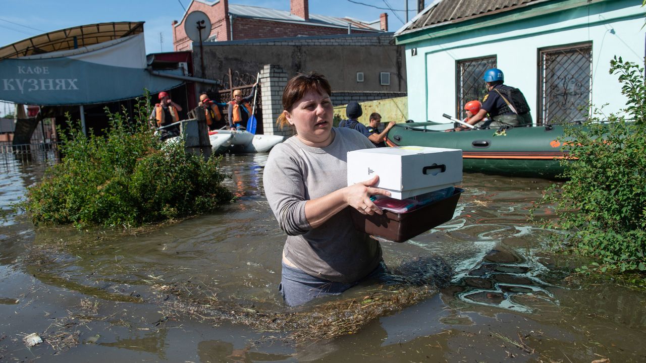 卡霍夫卡大坝溃决后，一名妇女从齐腰深的水中从赫尔松的家中取回一些物品。