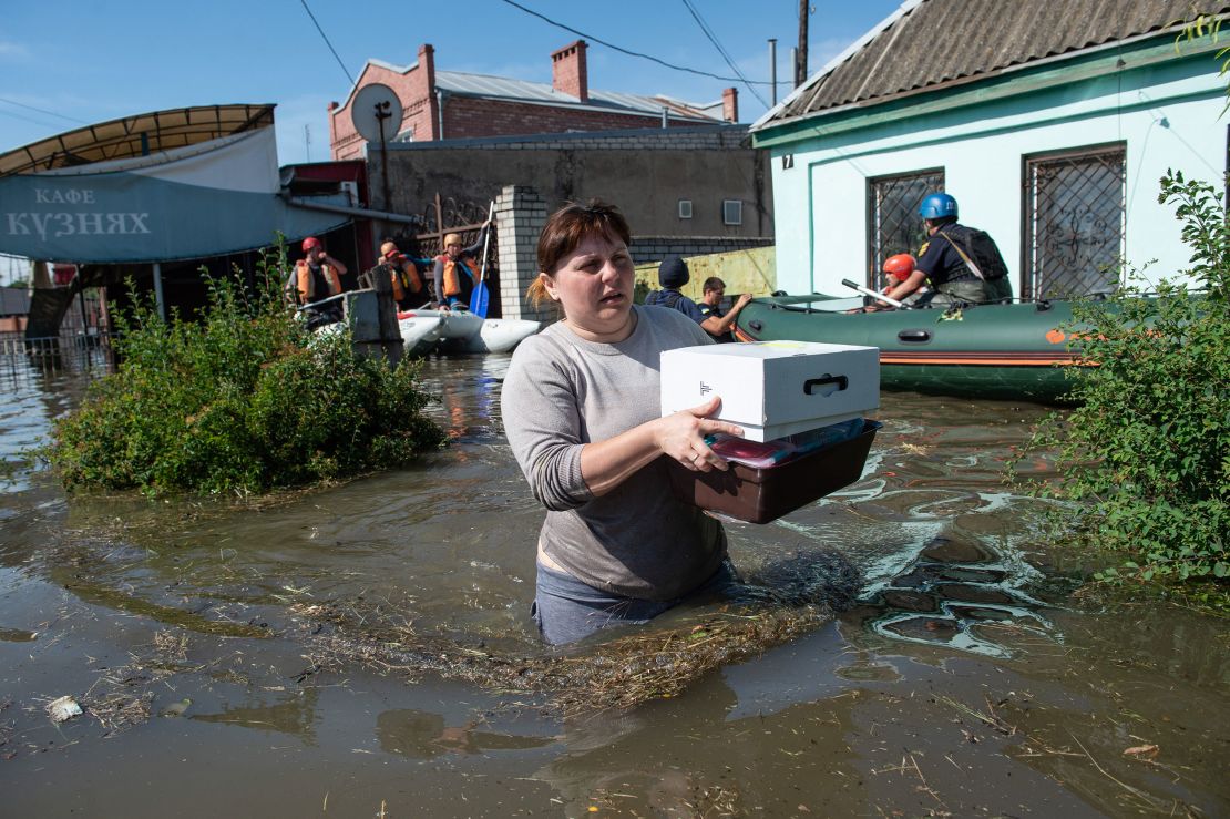 A woman wades through waist-high water after retrieving some belongings from her home in Kherson after the bursting of the Kakhovka dam. 