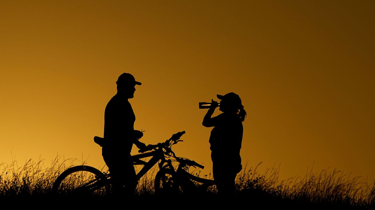 Cyclists take a water break on a June 2023 evening ride during a heat wave in San Antonio.