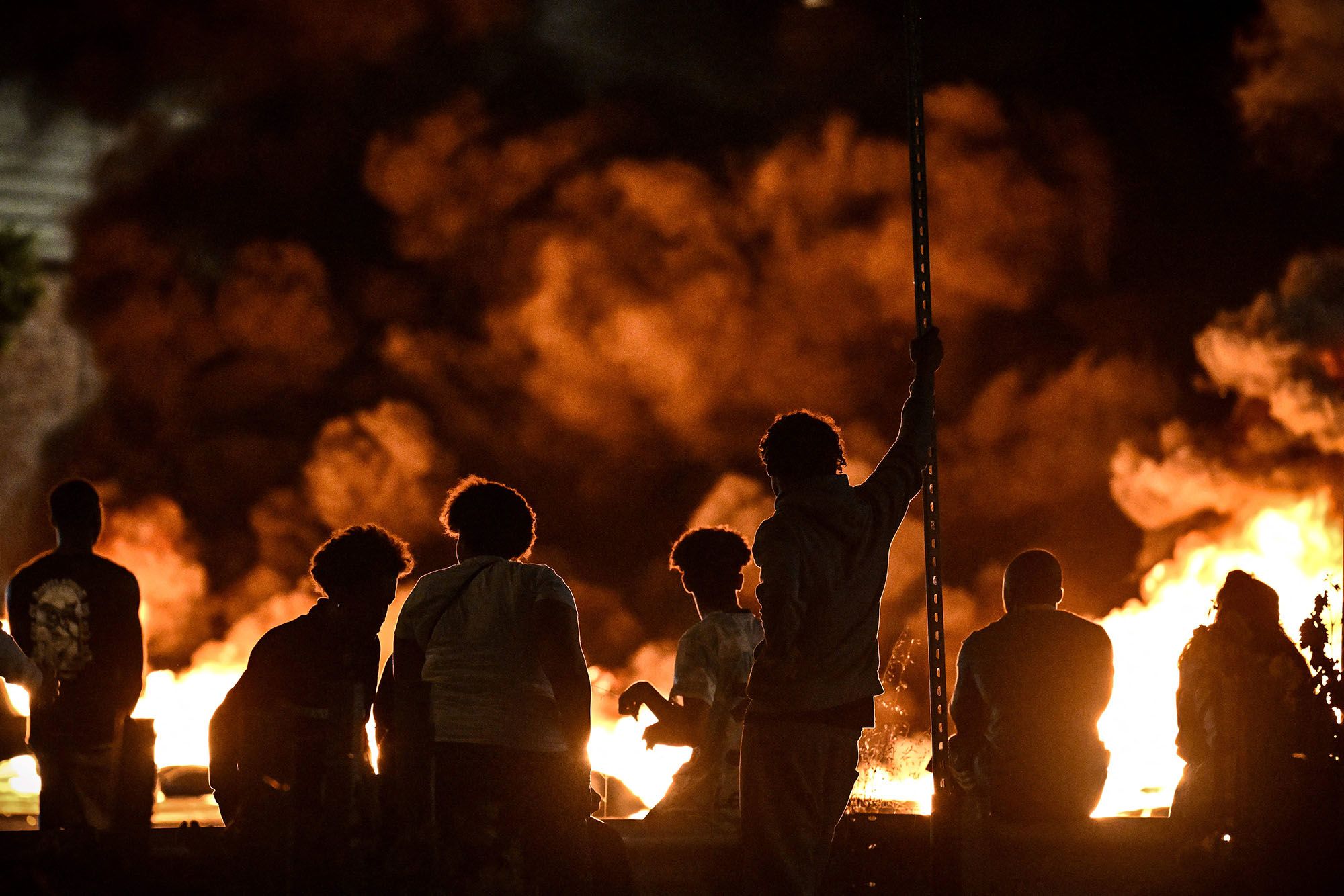 People look at burning tires blocking a street in Bordeaux, France, on Thursday, June 29.