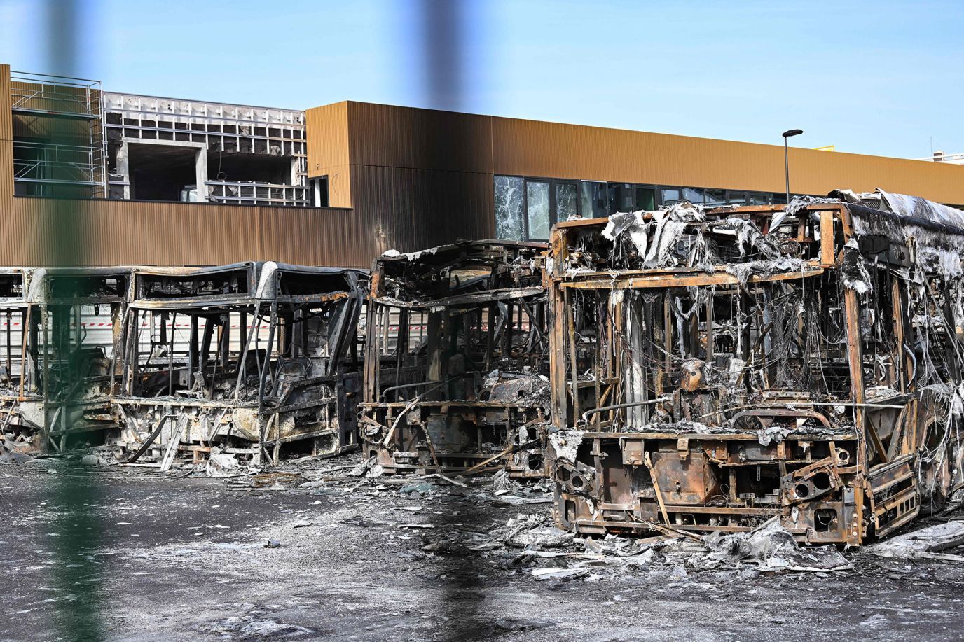Burnt buses can be seen through the gates at the Fort d'Aubervilliers bus terminal in Aubervilliers, France, on June 30.