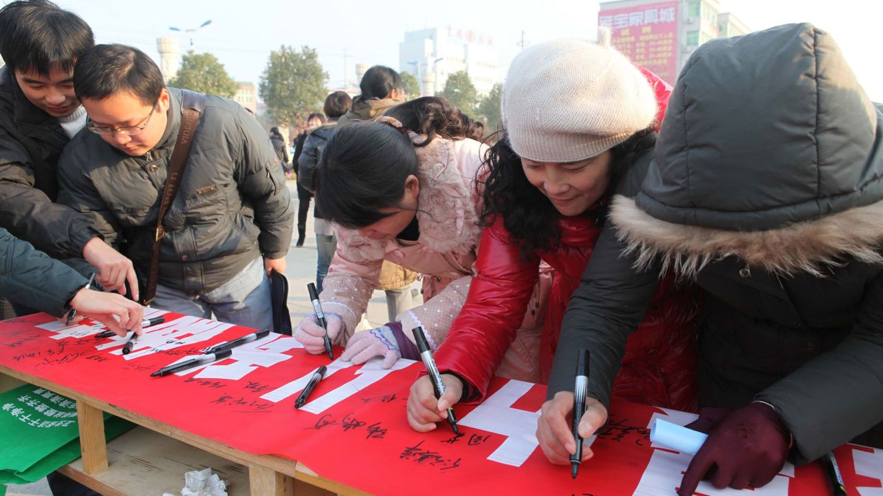 Volunteers in Ma Anshan city, Anhui province sign their names on a banner against domestic violence on December 14, 2011. 