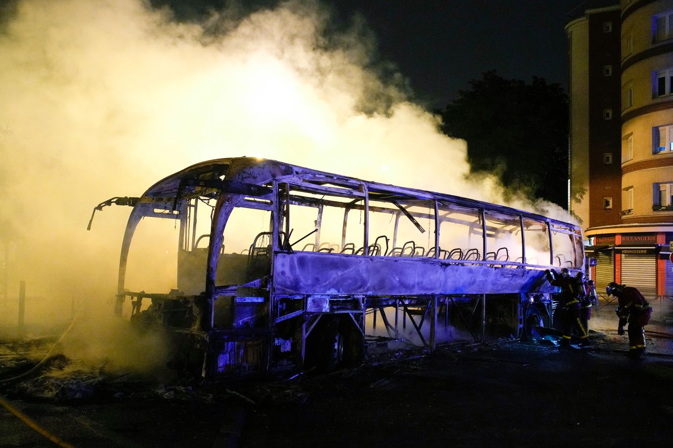 Firefighters use a water hose on a burnt bus in Nanterre, France, on July 1.