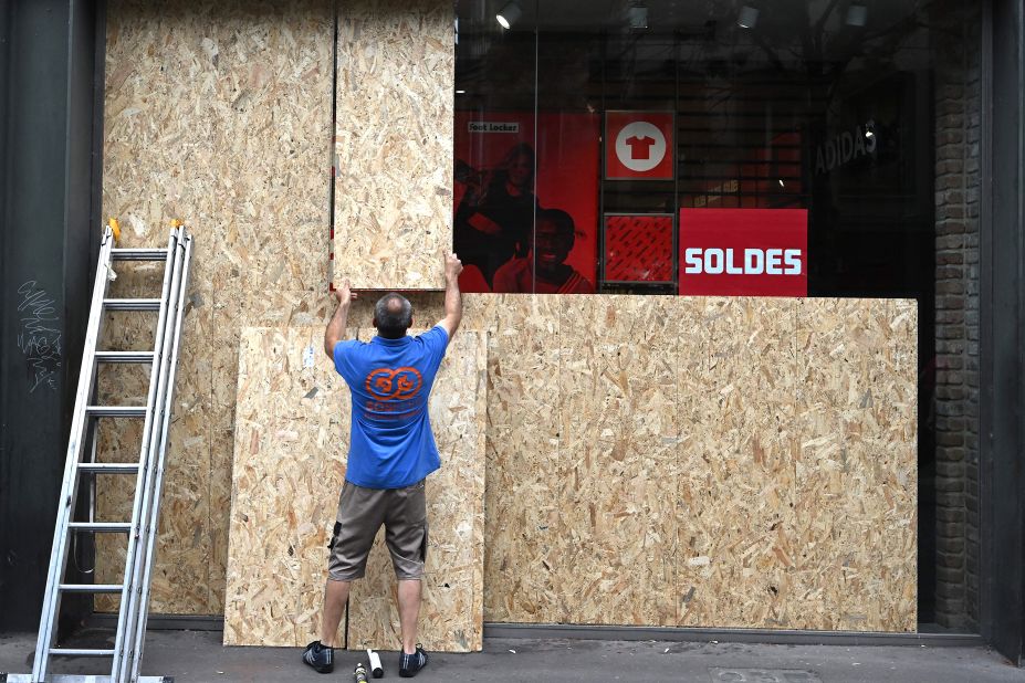An employee boards up shop windows on July 1, following a night of protests in Strasbourg, France.