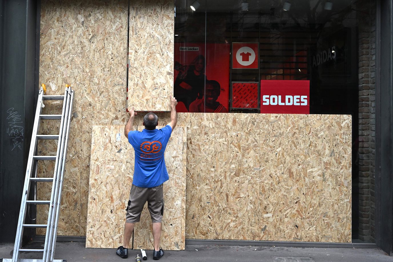 An employee boards up shop windows on July 1, following a night of protests in Strasbourg, France.