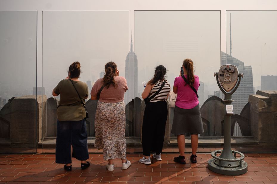 People look out at a hazy Manhattan skyline from the Rockefeller Center viewing deck Friday, June 30, in New York.