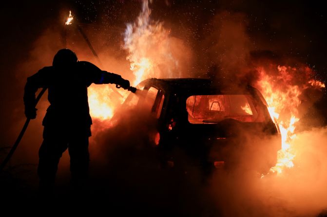 A French firefighter works to extinguish a burning car in Tourcoing, France, on July 2.