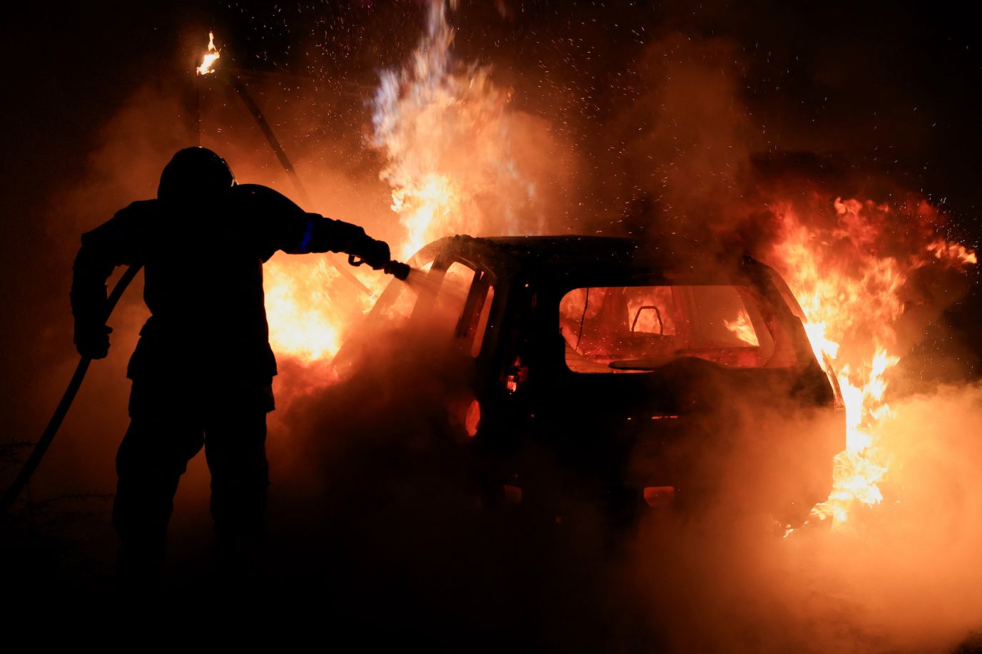 A French firefighter works to extinguish a burning car in Tourcoing, France, on July 2.