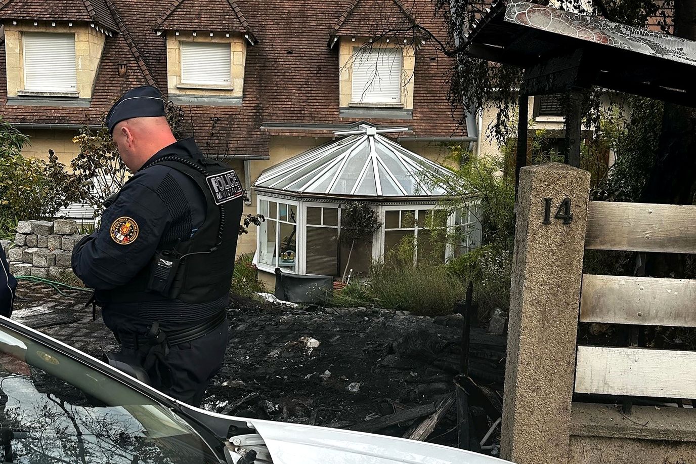 A police officer stands in front of the damaged home of Vincent Jeanbrun, the mayor of L'Haÿ-les-Roses, after <a href=