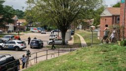 Residents watch as Baltimore Police investigate the site of a mass shooting in the Brooklyn Homes neighborhood on July 2, 2023.