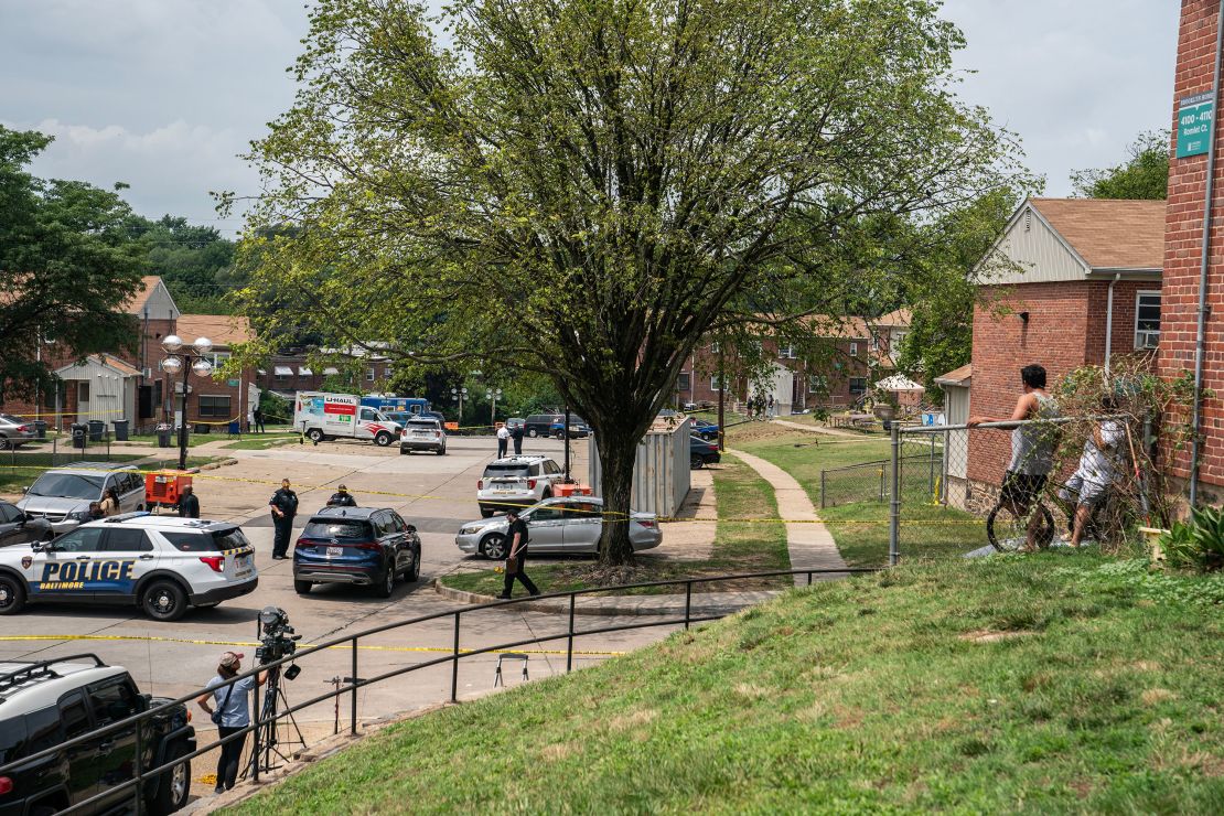 Residents watch as Baltimore police investigate the site of a mass shooting in the Brooklyn Homes neighborhood on July 2, 2023.