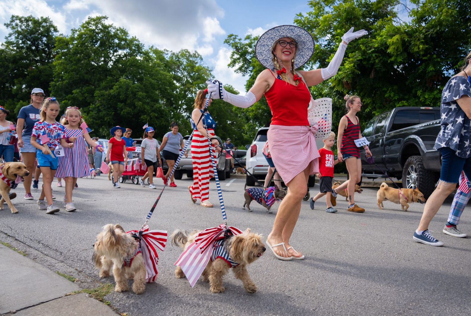 Angela Plunkett walks her dogs, Foxy and Bebe, during a patriotic pet parade Saturday in Bastrop, Texas. Plunkett and her dogs took second place in the look-alike category of the competition.