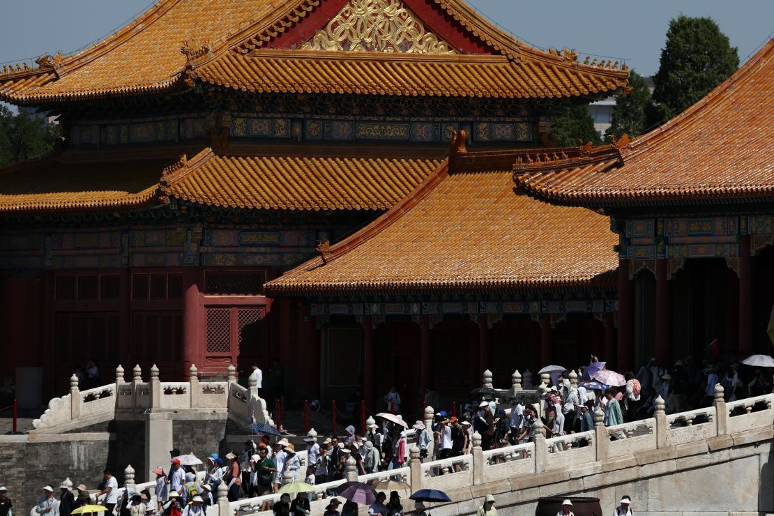 Tourists use umbrellas and protective clothing to shade from the sun at the Palace Museum in Beijing as the city's temperature reaches 39 degrees Celsius on June 29, 2023.