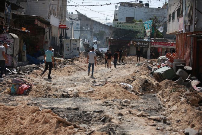Palestinians walk on the damaged streets of Jenin.