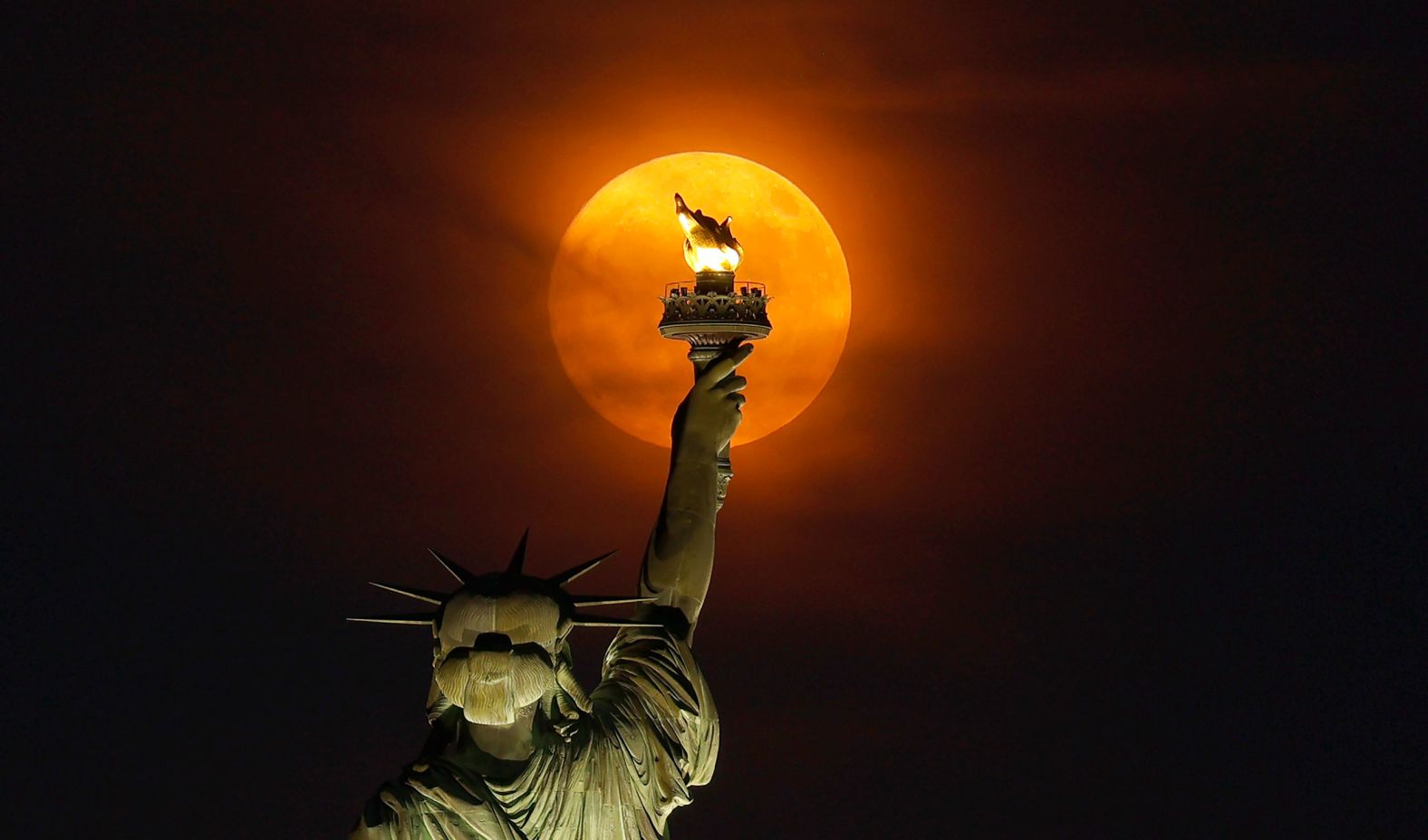 A full moon is seen behind the Statue of Liberty on Sunday.