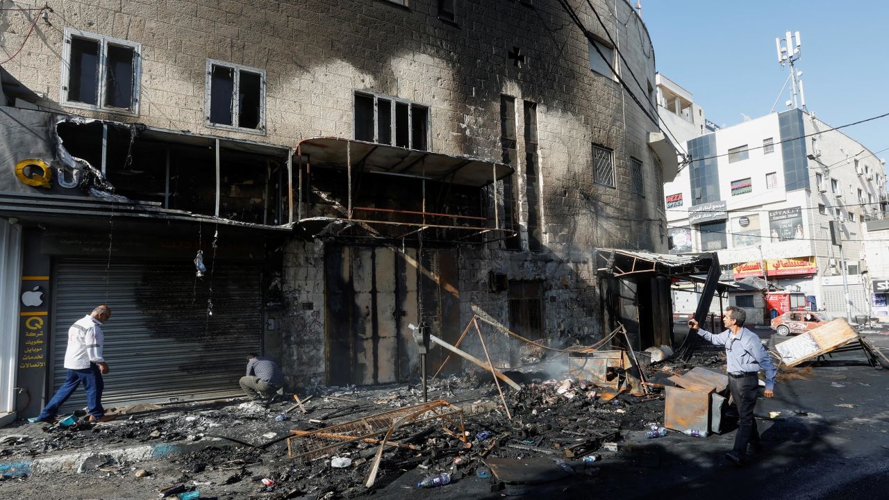People walk past debris and a building damaged amid an Israeli military operation, in Jenin, in the Israeli-occupied West Bank on July 4.